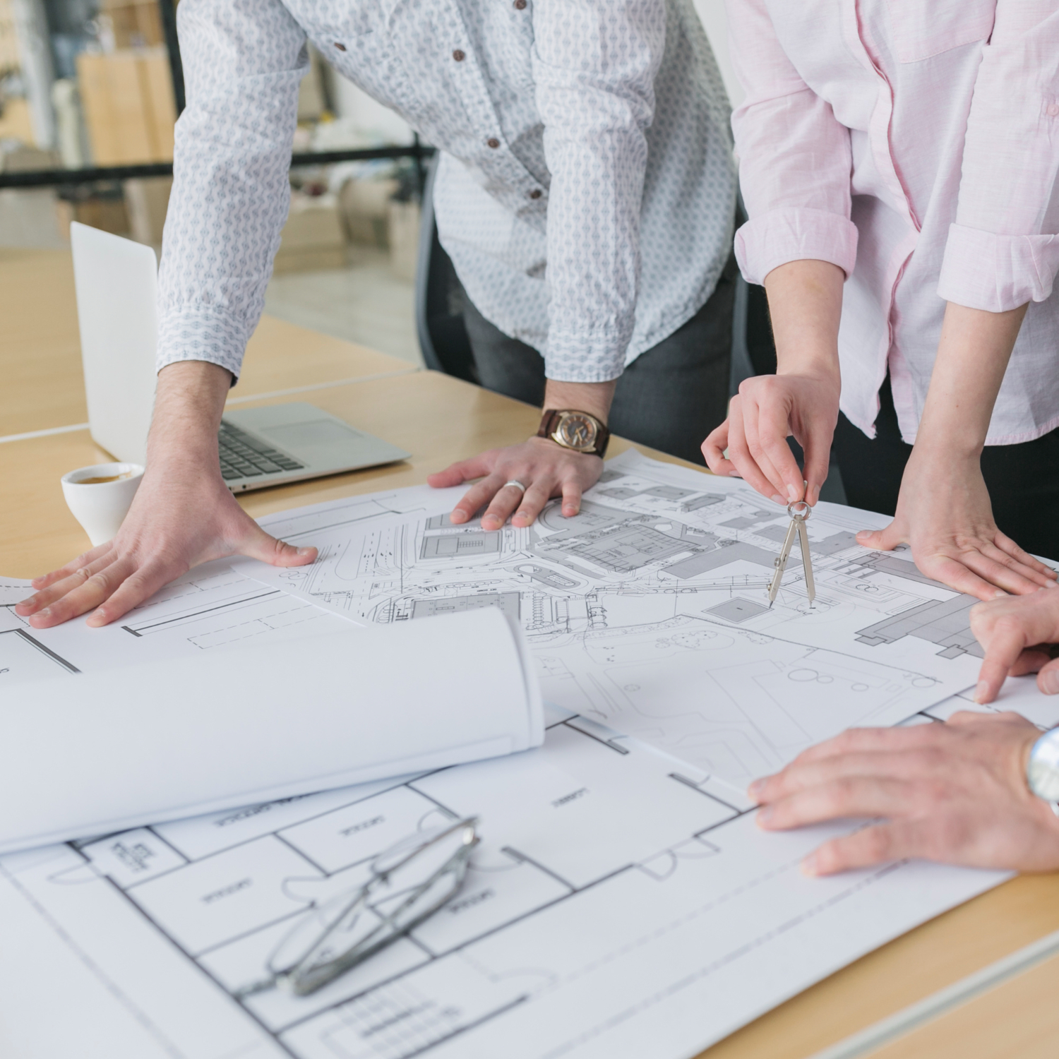 Real estate professionals collaborating over architectural blueprints with measuring tools during a property development planning meeting