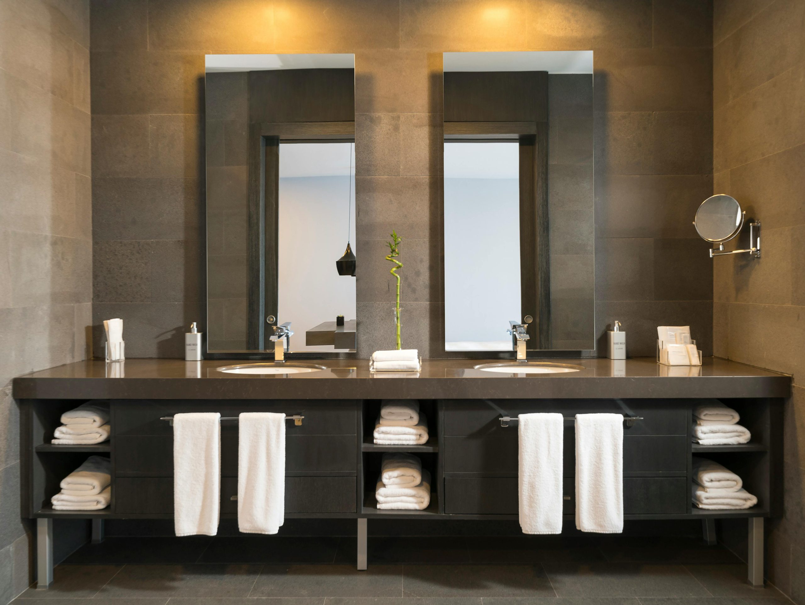 Elegant double sink bathroom vanity with illuminated mirrors, rolled white towels, and modern amenities in a luxury San Miguel property
