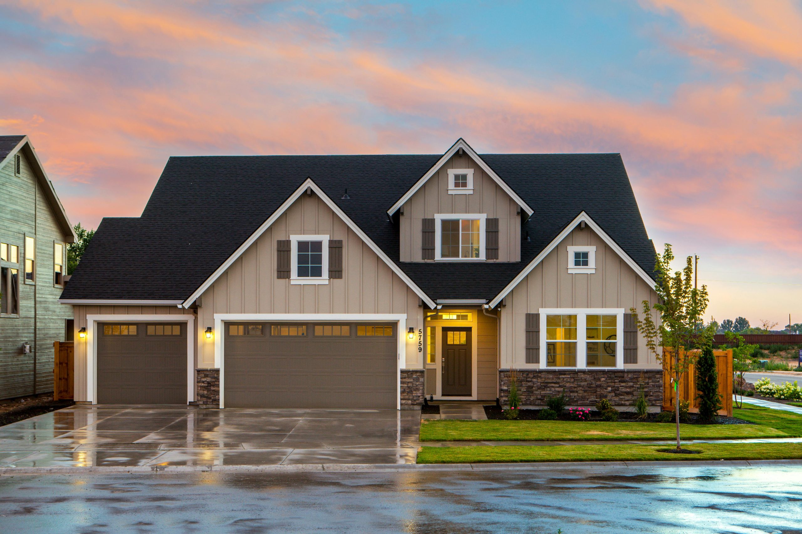 Elegant suburban home with three-car garage, stone accents, and beautifully landscaped yard captured during a peaceful sunset in Texas.